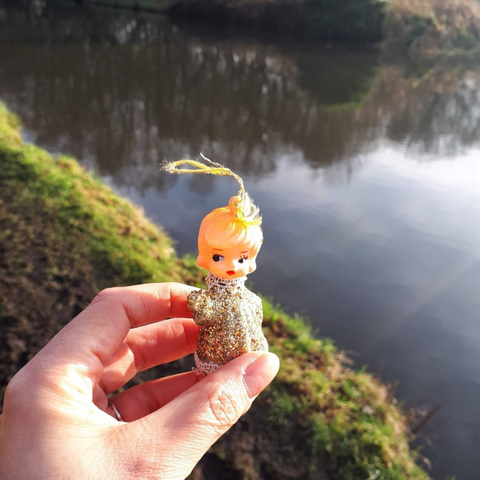a vintage gold angel ornament held in hand next to a village canal