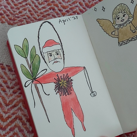 ink and coloured pencil drawings of a Santa ornament and angel in a sketchbook