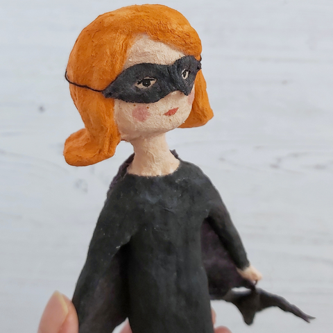 Close up of spun cotton bat girl's face, wearing a bandit mask, against a white background.