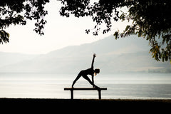 Yoga in park on bench in front of a lake