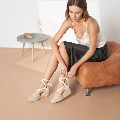 Girl putting on beige lace-up espadrille wedges. Handcrafted espadrilles made in Spain.