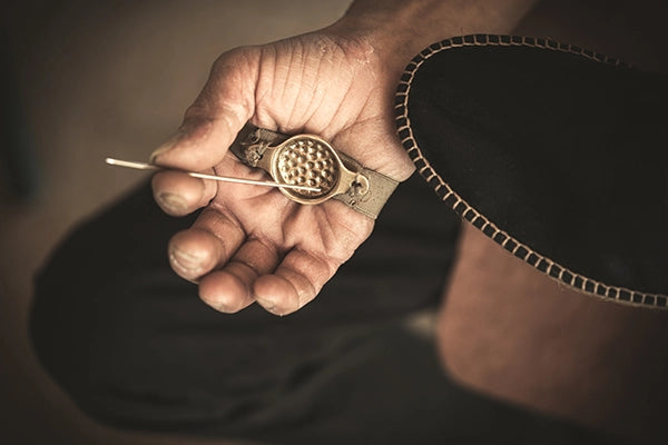 A hand holding tools for stitching espadrilles