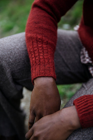 the forearm of a woman, featuring the detail stitching of a red sweater