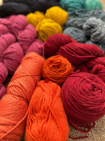 a heap of yarn in various shades with vivid oranges in the forefront