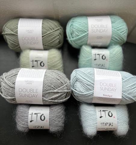 Skeins of wool and mohair yarns in icy cool colors on a dark surface