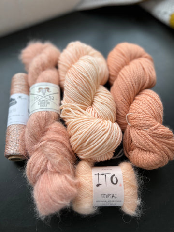 Different yarns in various shades of peach on a black table