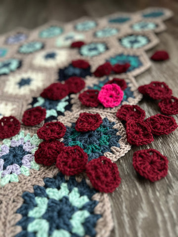 little crocheted red hexagon centers sprinkled on a portion of a blanket.