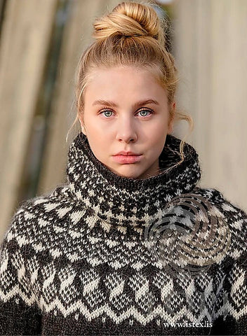 Young blonde woman wearing a black and white sweater with a cowl neck.