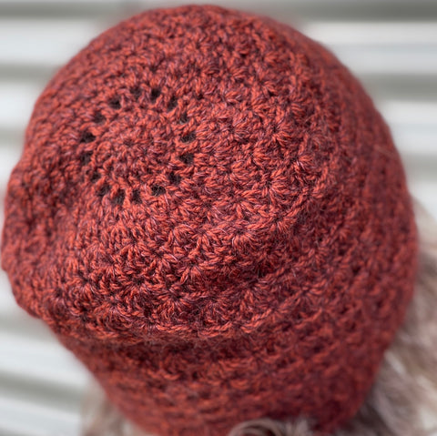 A russet colored hat pictured from behind against a corrugated metal background