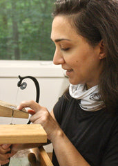 Brooke hand sawing sterling silver at her jeweler's bench.