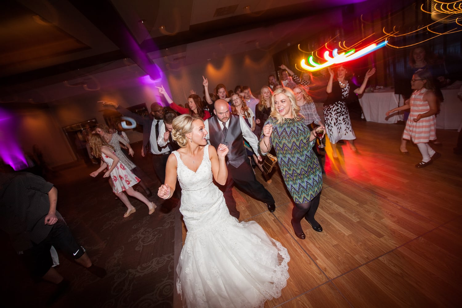 A bride is dancing with guests at her wedding reception.