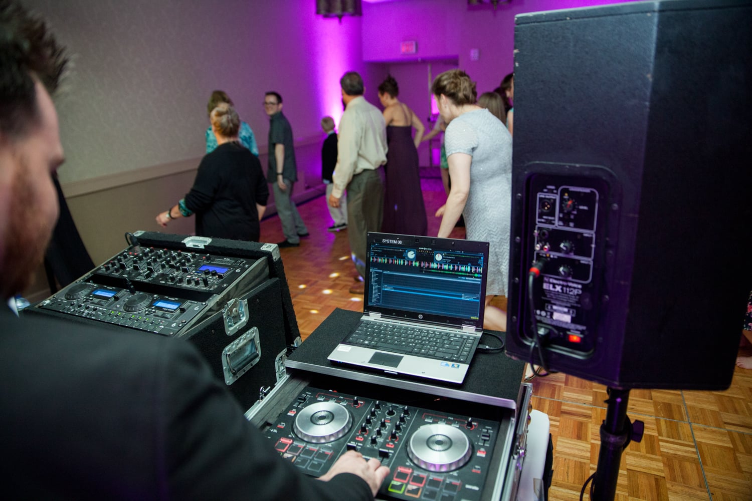 A DJ is behind his equipment at a wedding reception