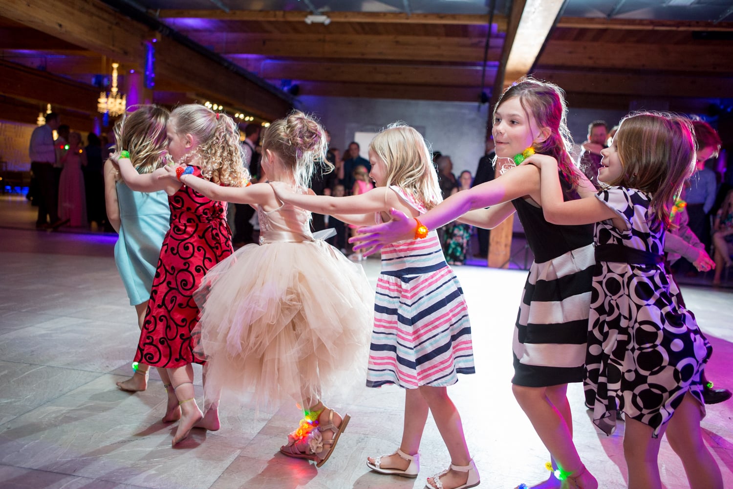 Kids hold onto each other going around a dance floor in a line