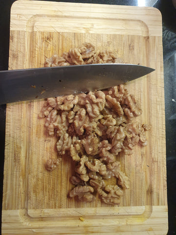 walnuts being chopped with a knife on a cutting board