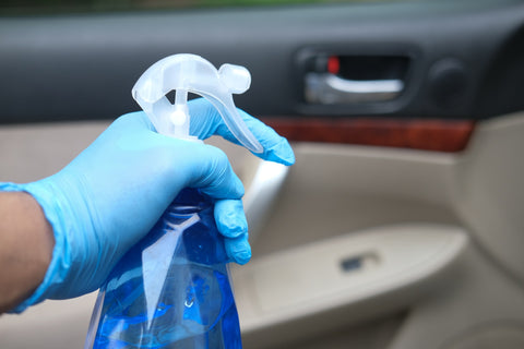 gloved hand with spray bottle cleaning inside of a car to convey the importance of interior car detailing