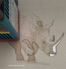 Rhino image being laser etched. Design by Sarah Soward. Part of the design are also cut out so that other color shows through.