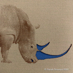 Laser etched rhino by Sarah Soward. The rhino's horns are cut out so that other fabric shows through in blue.
