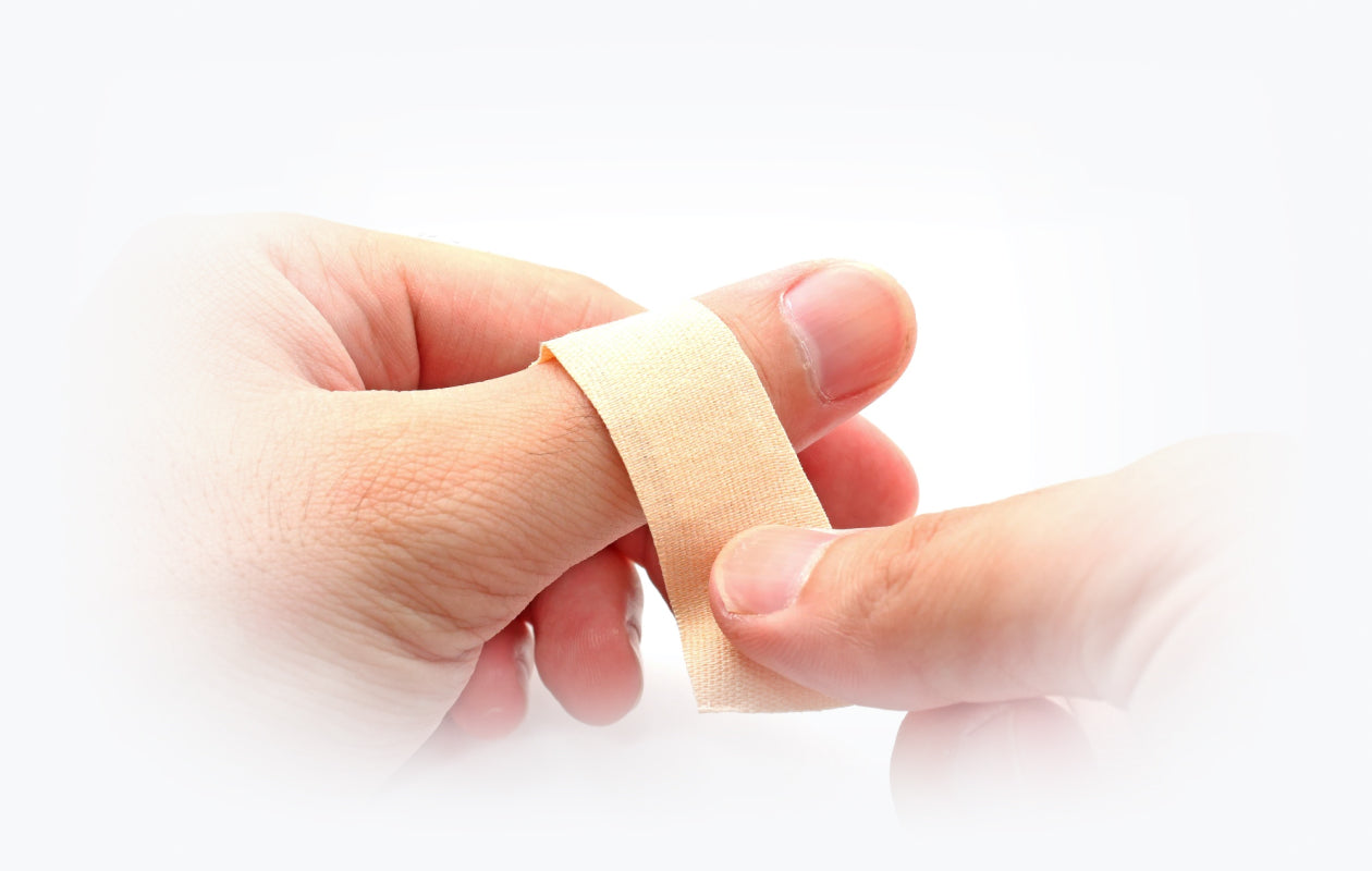 Photo of person wrapping band aid around thumb because of a cut or wound