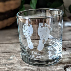 small highball glass with nicu baby footprints etched on the side with the words "Dad est. 2017" engraved below.