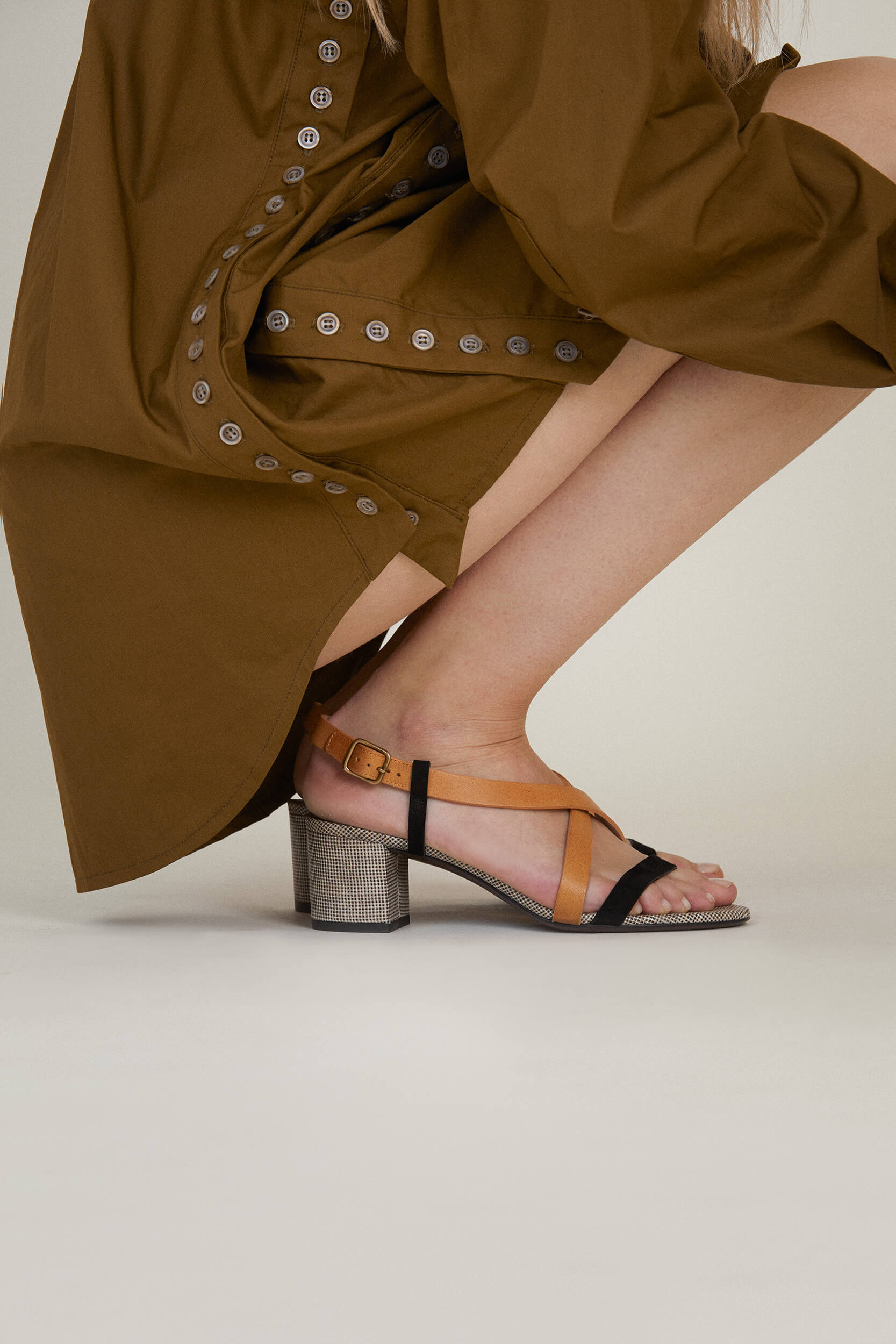 Photographie portée d'une sandale d'été à talon de 5,5cm. Tige en cuir de veau camel, chèvre velours noir et toile de lin. Fabrication italienne. 