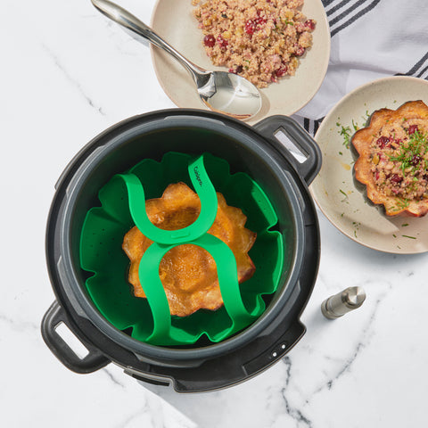 An acorn squash baking in a vegetable steamer in an Instant Pot