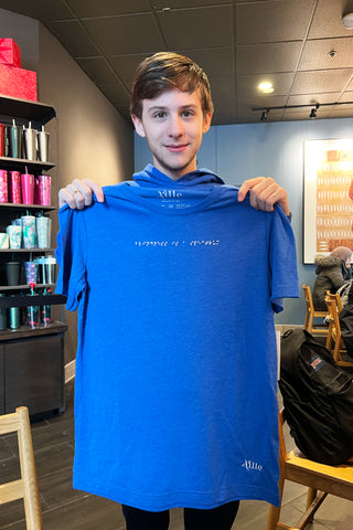 Person holding blue t-shirt with braille