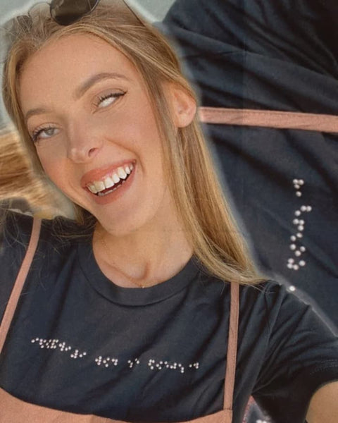 White visually impaired woman with blonde hair wearing her black braille t-shirt