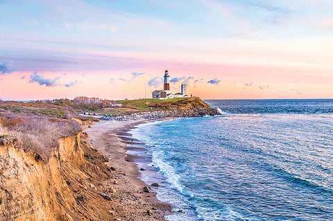 Ocean view of Montauk Point Lighthouse in Montauk, New York at sunset with a small cliff on the left overlooking the water on the right