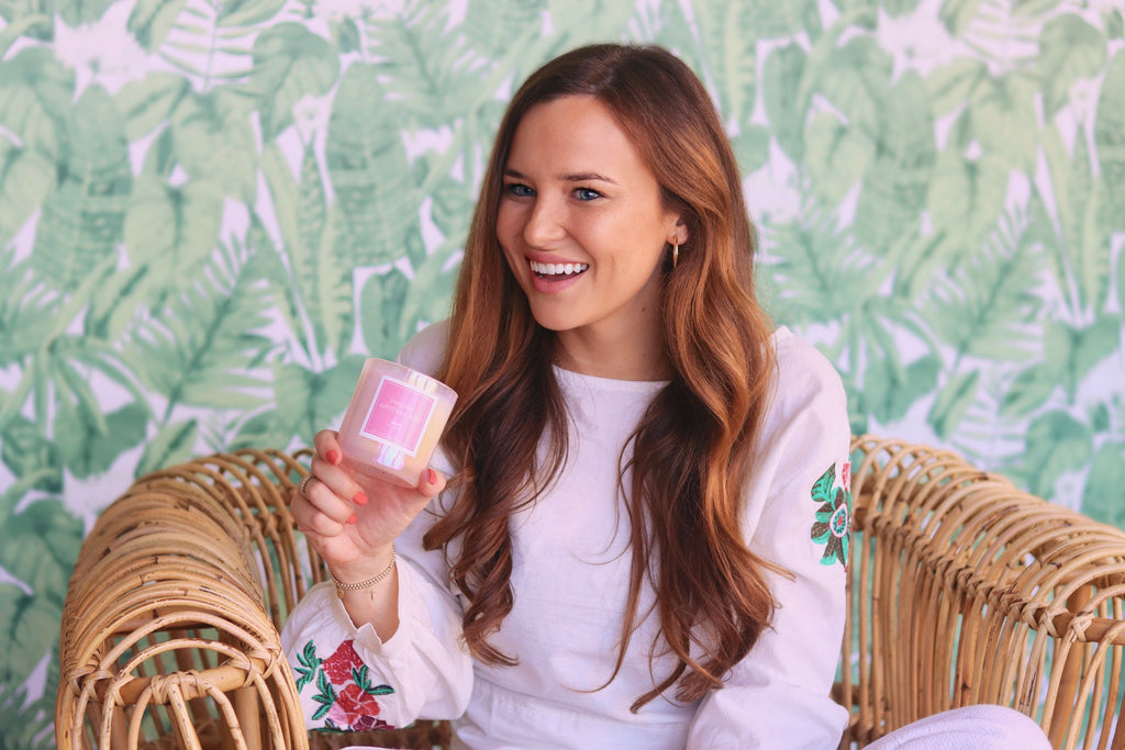 Malibu Apothecary Founder Claire Ellis sitting on a chair holding our holographic iridescent pink candle