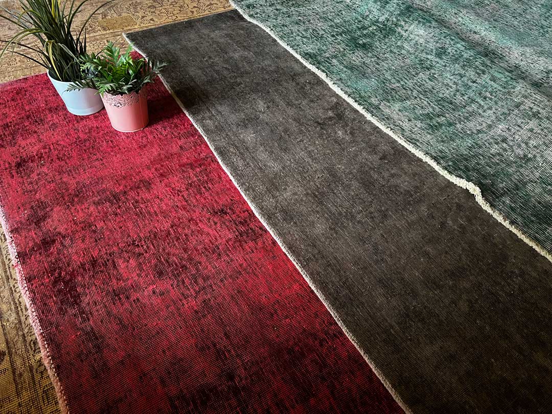overdyed colorful hand knotted rugs stacked on top of each other