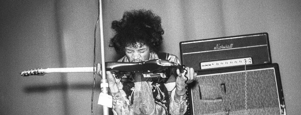 Jimi Hendrix playing guitar with his teeth