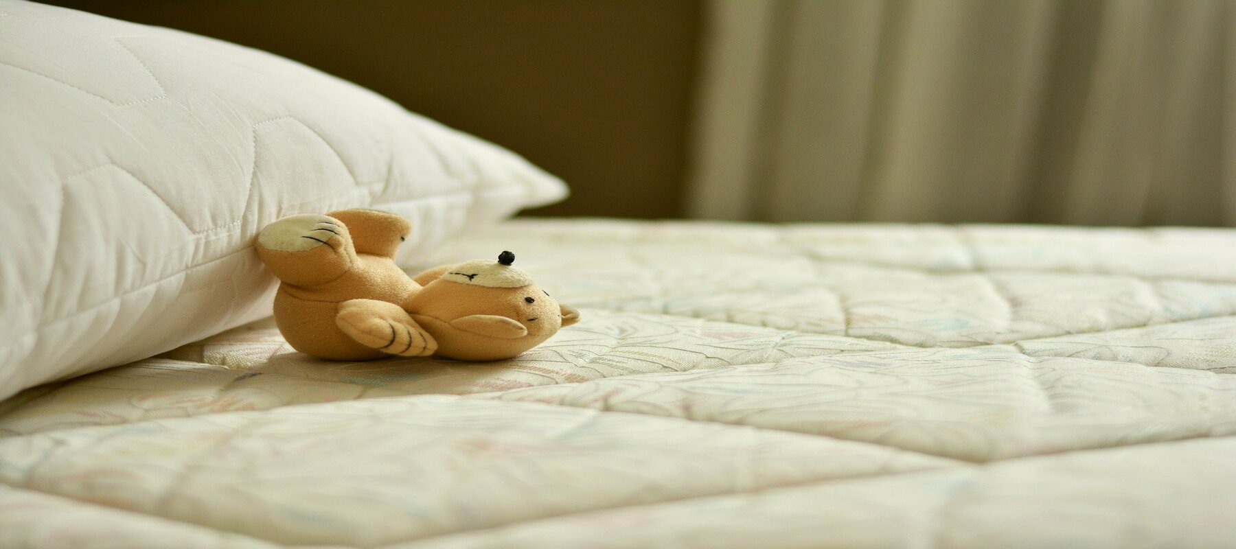 Petit ourson qui est allongé sur un lit sans parure
