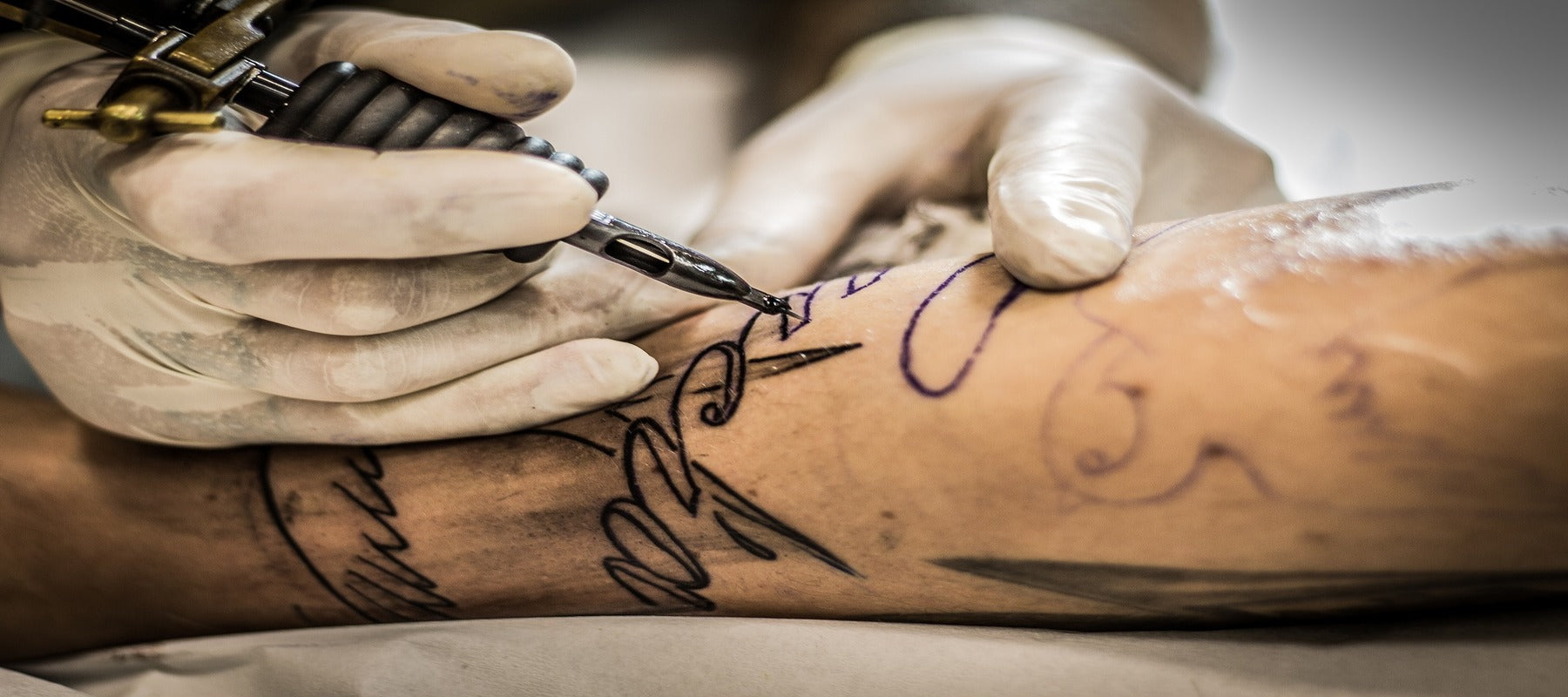 Homme en train de se faire tatouer un tatouage tribal