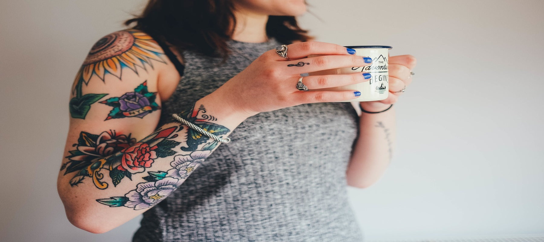 Femme qui porte un tatouage bouddha a l'avant bras tout en buvant un café