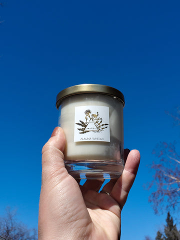 hand holding luxury air element soy intention crystal infused candle against bright blue sky