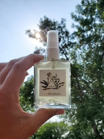 air sign crystal infused mist in palm of hand with trees and sun in the background