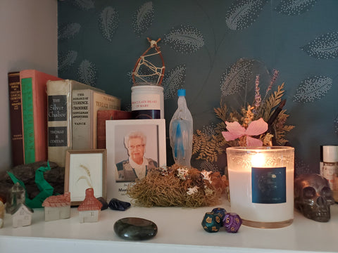 blue and gold label on waning moon lunar soy candle on altar with ancestors crystals and books