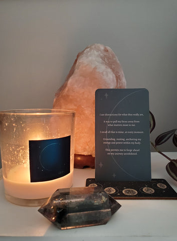 altar with lit new moon lunar intention candle, crystal, oracle card, and salt lamp