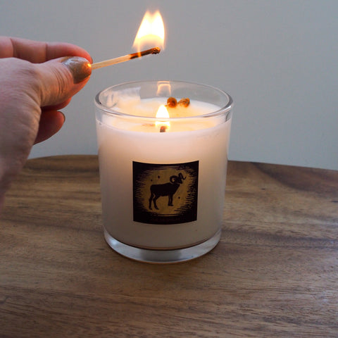 hand with lit match lighting aries crystal infused soy intention zodiac candle