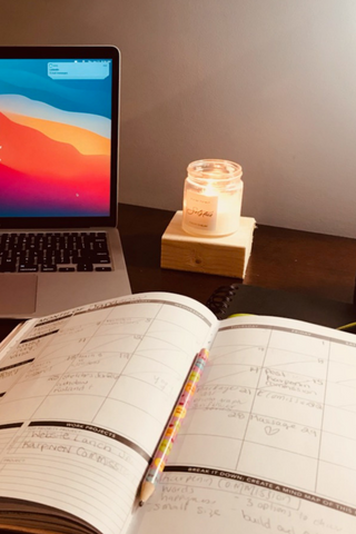 desk with solstice candle, laptop, and journal
