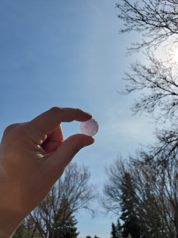 purple carved crystal moon with hand holding up to the sky