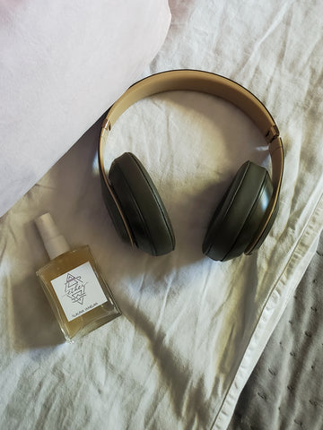 luxury crystal infused ritual mist on white bedding with beats headphones