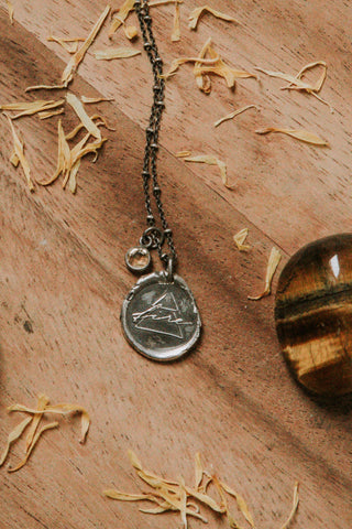 fire alchemical symbol silver medallion talisman necklace on wooden background