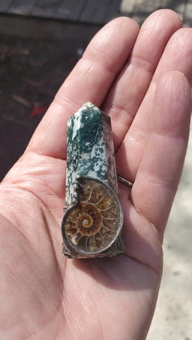 green and white crystal talisman ritual wand with brown ammonite fossil in palm of hand