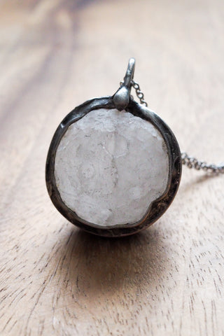 large quartz crystal moon healing silver talisman necklace on wooden tray