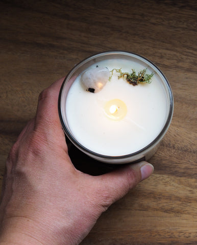 hand holding luxury soy candle topped with moss and crystal