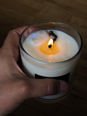 hand holding luxury soy candle topped with moonstone crystal