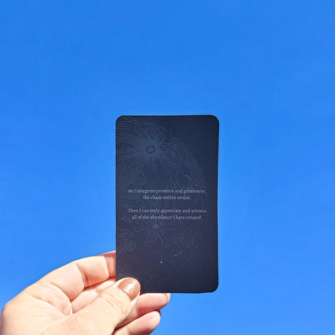 hand holding blue affirmation card against bright blue spring sky