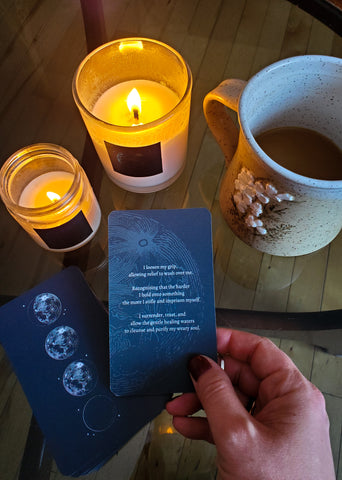 hand holding tarot oracle card with lit candles and coffee mug in background