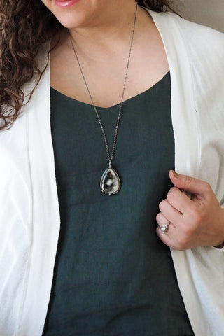 woman in blue top wearing healing crystal talisman necklace